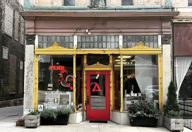 Exterior of Amilinda restaurant at 315 E Wisconsin Avenue, Milwaukee, with yellow storefront and red door